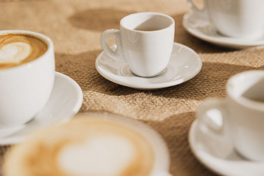 Tazas servidas con cafe con leche sobre una mesa de lona de saco de café