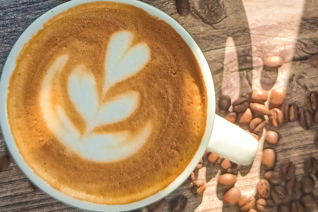 taza de cafe espresso centrada con un latte art sobre una mesa de madera y granos de café 