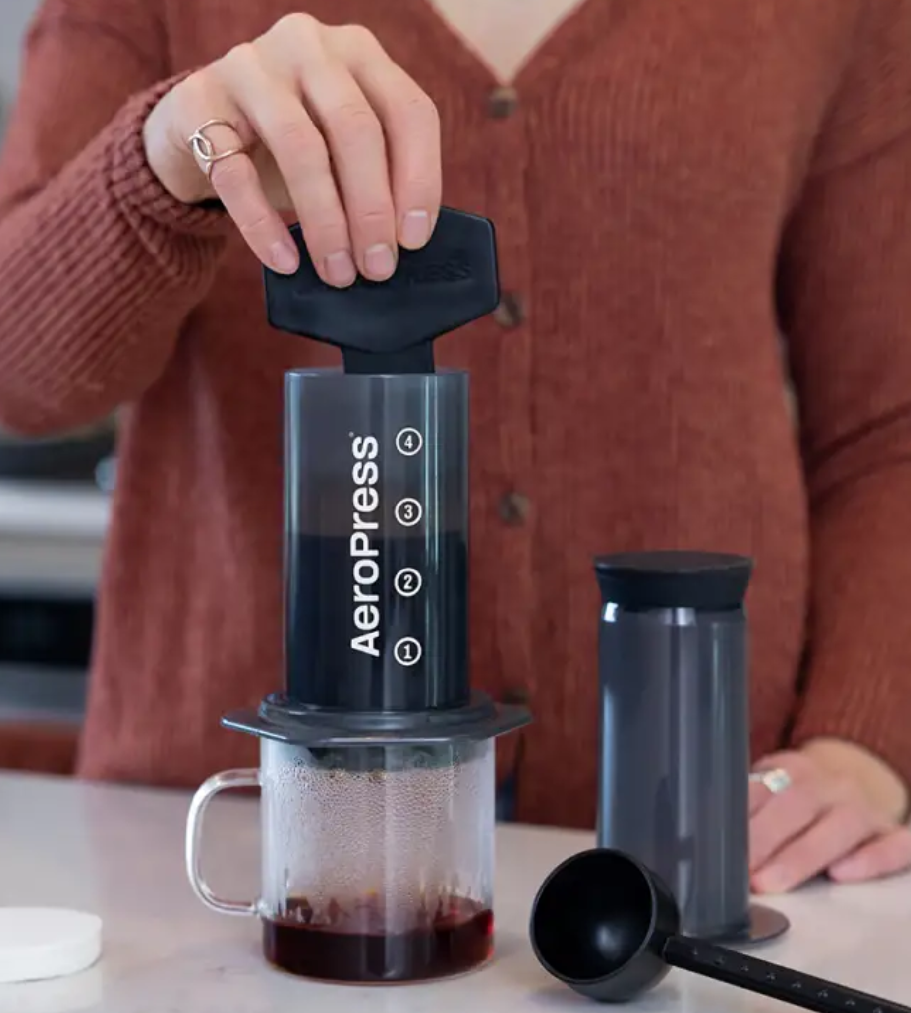 Persona preparando café con la Aeropress, mostrando su uso práctico