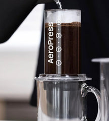 Sirviendo café preparado con AeroPress usando filtros de papel, taza lista para disfrutar